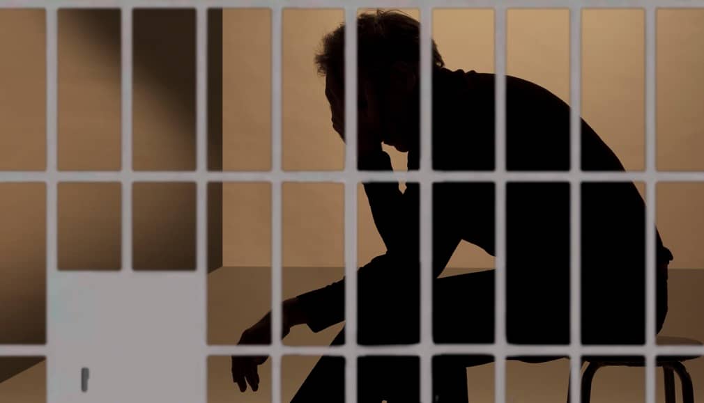 Inmate sitting in jail cell looking dejected