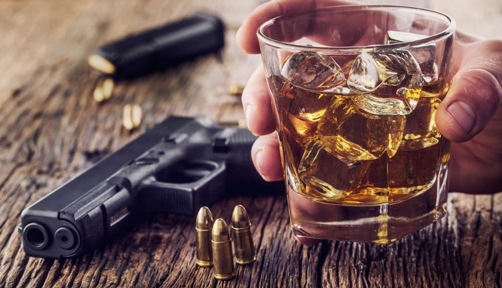 Gun and alcohol. 9mm pistol gun and cup whiskey cognac or brandy.